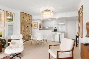 a living room with white chairs and a kitchen at Oscar on Main resort Walk to beach and Tedder Ave in Gold Coast