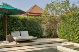 a patio with a chair and an umbrella next to a pool at Banyan Tree Phuket in Bang Tao Beach