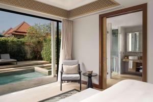 a bedroom with a view of a pool and a chair at Banyan Tree Phuket in Bang Tao Beach