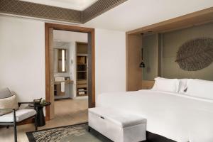 a bedroom with a large white bed and a chair at Banyan Tree Phuket in Bang Tao Beach