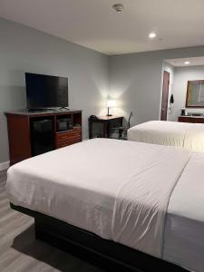 a hotel room with two beds and a flat screen tv at SureStay by Best Western McAlester in McAlester