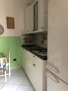 uma cozinha com armários brancos e um frigorífico branco em ZIO DOMENICO Al Vicolo em Castellabate