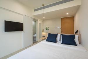 a bedroom with a large white bed with blue pillows at Hotel Ever Spring - Penghu in Magong