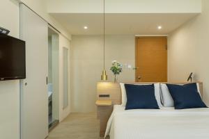 1 dormitorio con 1 cama grande con almohadas azules en Hotel Ever Spring - Penghu, en Magong