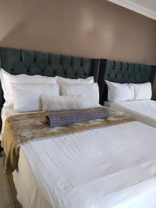 two beds with white sheets and a green headboard at Soma Guesthouse in Groblersdal