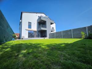 a white house with a grassy yard in front of it at Armina's Residence in Dumbrăviţa