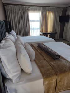 una camera d'albergo con due letti con cuscini e un telecomando di Soma Guesthouse a Groblersdal