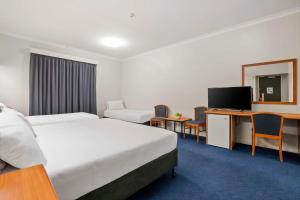 a hotel room with two beds and a tv at Metro Hotel Perth City in Perth