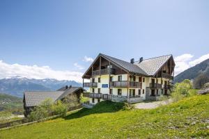 a house on a hill with mountains in the background at Les Alpages du Corbier C101 in Villarembert