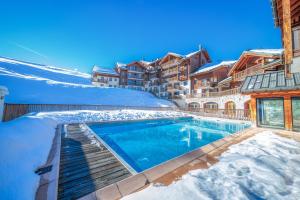 a swimming pool covered in snow next to a building at Les Alpages du Corbier C101 in Villarembert