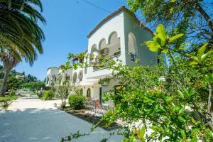 un grande edificio bianco con alberi di fronte di Vassilis Paradise Garden Aparthotel ad Agios Georgios Pagon