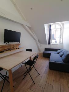 ein Wohnzimmer mit einem Tisch und einem blauen Sofa in der Unterkunft Studio plein de charme - 2 in Orléans
