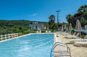una piscina con sedie a sdraio e ombrelloni di Vassilis Paradise Garden Aparthotel ad Agios Georgios Pagon