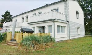 ein weißes Haus mit einem Zaun davor in der Unterkunft Nilles Huuske - Luxusferienwohnung in Ostseebad Sellin