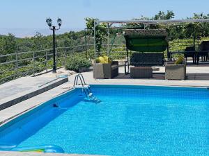 einen blauen Pool mit Stühlen und einem Tisch in der Unterkunft Chalets in the middle of Ajloun forests شاليه و مزرعة في وسط غابات عجلون in Adschlun