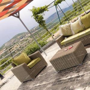 eine Terrasse mit Korbstühlen, einem Tisch und einem Sonnenschirm in der Unterkunft Chalets in the middle of Ajloun forests شاليه و مزرعة في وسط غابات عجلون in Adschlun