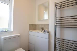 a white bathroom with a sink and a toilet at Saltwhistle View- Beachside Luxury, Stunning Views in Teignmouth