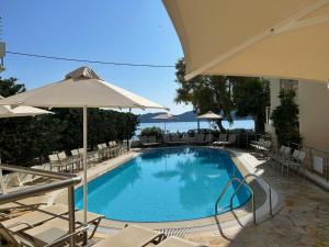 a swimming pool with chairs and an umbrella at Eucalyptus suite sea view in Karavomylos