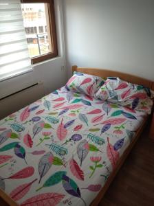 een bed met een kleurrijk dekbed en een raam bij The Nest in Vrnjačka Banja