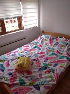 een bed met een kleurrijk dekbed en 2 handdoeken erop bij The Nest in Vrnjačka Banja