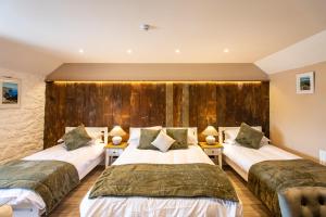 two beds in a room with wooden walls at Kings Arms in Penzance