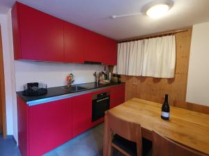 cocina con armarios rojos y mesa de madera en Gadä 2 en Reckingen - Gluringen