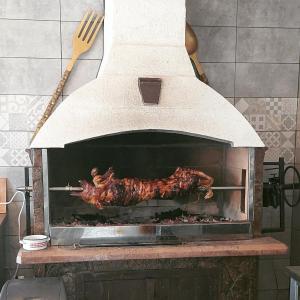 a roast chicken cooking in an outdoor oven at Imanje sa bazenom in Obrenovac