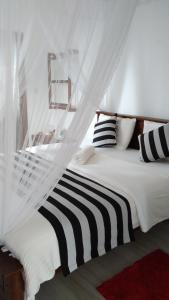 Cama blanca con almohadas blancas y negras y ventana en Holly House Homestay, en Ella