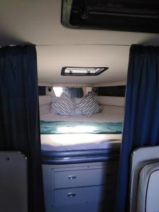 a bed in the back of a train with blue curtains at l ile sur mer in Empuriabrava