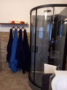 a bathroom with a shower with blue dresses hanging on a rack at Domus Shardana in Gonnesa