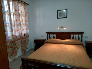 1 dormitorio con cama con marco de madera y cortinas en Domus Shardana en Gonnesa