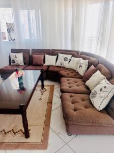 ein Wohnzimmer mit einem braunen Sofa und einem Glastisch in der Unterkunft B&B/chambres d'hôtes in Antananarivo