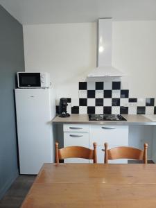 cocina con mesa, 2 sillas y nevera en Appart 3 chambres, en Noyen-sur-Sarthe