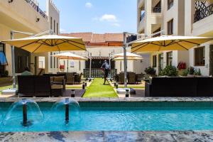 una piscina con sombrillas, mesas y sillas en Kandiz 2 Bedroom Apartment en Nairobi