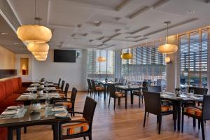 a dining room with tables and chairs and windows at La Suite Dubai Hotel & Apartments in Dubai