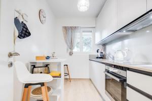 a white kitchen with a stool and a sink at RELAX Camelia Apartment in Locarno