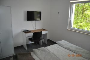 a bedroom with a desk with a bed and a television at Zimmervermietung Eberswalde in Eberswalde