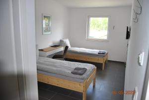 EberswaldeにあるZimmervermietung Eberswaldeのベッド2台、デスク、窓が備わる客室です。