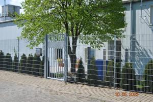 a fence with a tree in front of a building at Zimmervermietung Eberswalde in Eberswalde