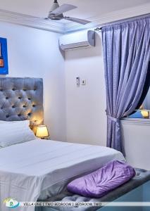 Un dormitorio con una cama con sábanas moradas y una ventana en D White Villas, en Old Yundum