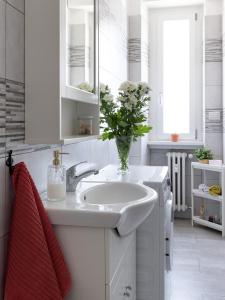 a white bathroom with a sink and a vase of flowers at Cosy flat in Cormano