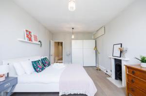 ein Schlafzimmer mit einem weißen Bett und einem Kamin in der Unterkunft WelcomeStay Colliers Wood Two Bed Apartment - Home Away from Home in London