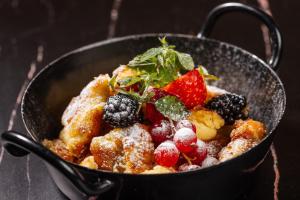 a bowl of food with fruit and powdered sugar at Hotel SeeRose in Bodensdorf
