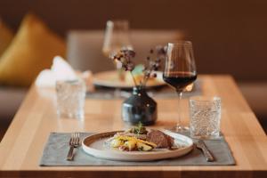 a table with a plate of food and a glass of wine at Hotel SeeRose in Bodensdorf