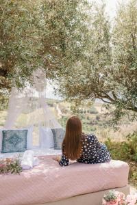 a woman sitting on a bed under a tree at Star Sleep Kalesia Heraklion in Heraklio Town