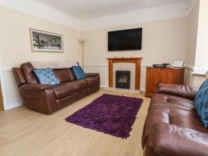 a living room with a leather couch and a fireplace at 11 Overdale Avenue in Wirral