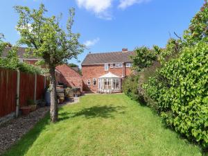 a house with a yard with a tree and a fence at 11 Overdale Avenue in Wirral