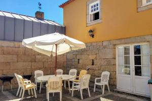 une table et des chaises avec un parasol en face d'un bâtiment dans l'établissement Confort, fun and leisure in Douro Rural Space, à Sande