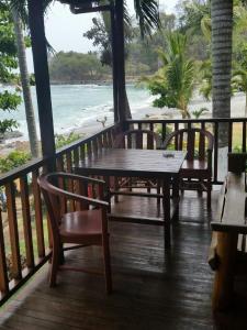 una terraza de madera con mesa y sillas y la playa en Hotel Cabinas Mar Y Cielo en Montezuma