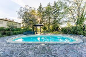 a swimming pool with an umbrella in a yard at Tuscan Skye - Villa Sofia with private swimming pool and garden in Barga